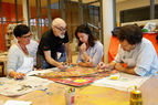 Zoom: Ein Workshop Leiter erklärt einer Gruppe die Vorgehensweise und Technik zur Gestaltung eines Bildes