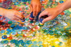 Zoom: Mit farbigen Stempeln wird von drei Händen ein Bild gestaltet