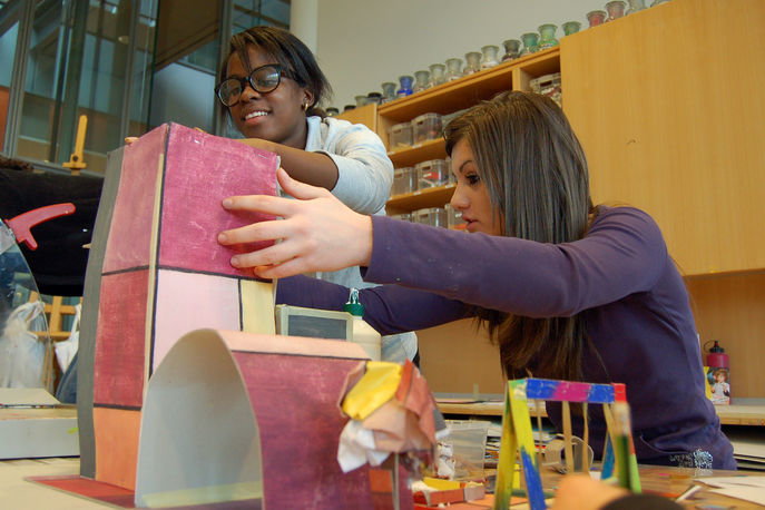 Zwei Mädchen bauen gemeinsam ein Modell aus Karton