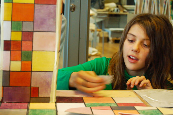 Foto eines Mädchens dass ein Werk mit farbigen Quadraten bearbeitet