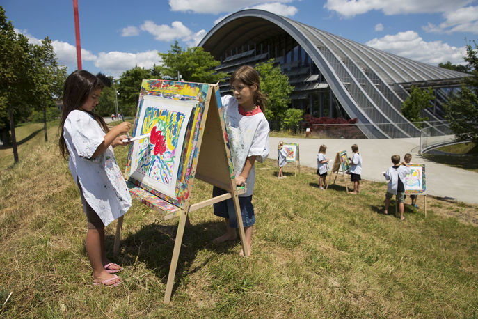 Zwei Mädchen die auf einer Staffelei vor dem Zentrum Paul Klee ein Bild malen