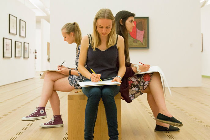 Drei Schülerinnen, welche sitzend verschiedene Gemälde abzeichnen