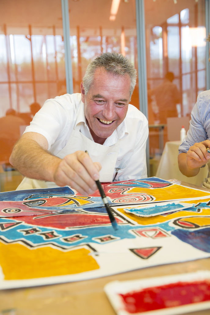 Ein glücklicher Mann gestaltet mit Pinsel und Farbe ein Bild